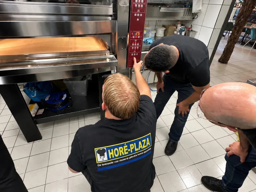 Monteur van Horé-Plaza legt de bediening van een nieuwe oven uit aan de ondernemer
